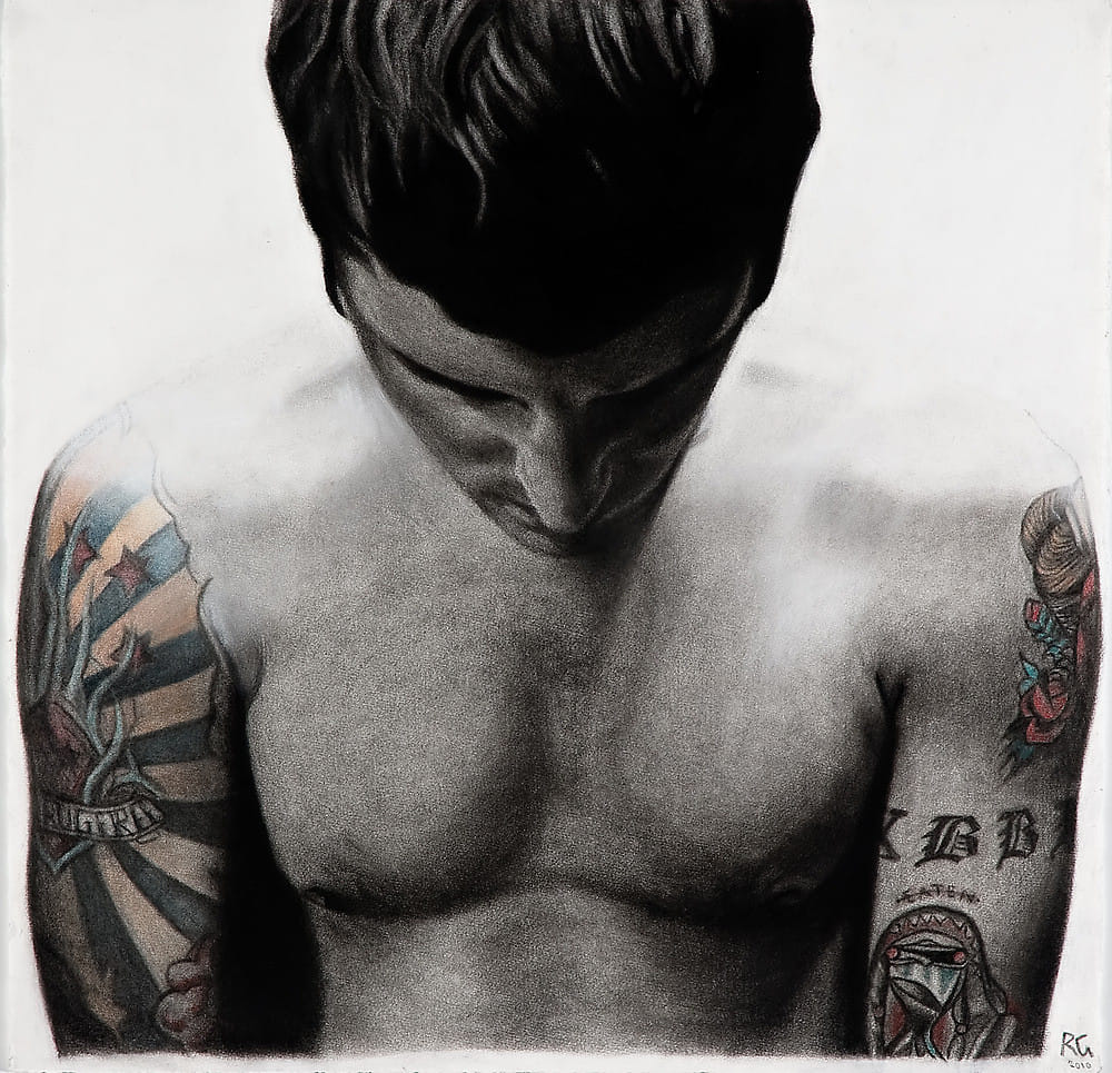 image of man looking downward with tattooed arms