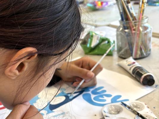 A teen working closely on a painting of Bluey