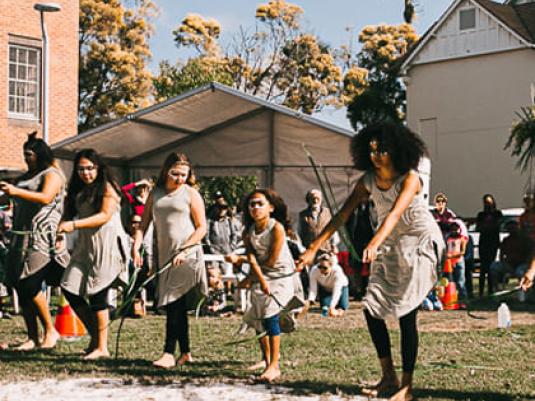 group of indigenous women and girls doing traditional dance with sticks