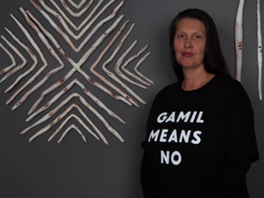 Artist Penny Evans in front of wall art made from ceramic