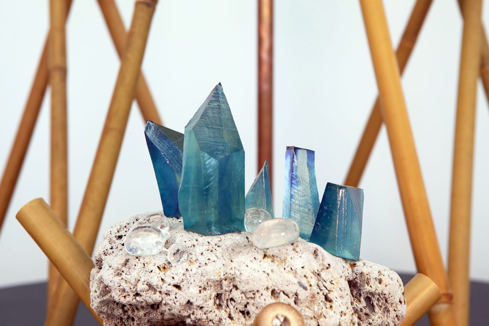Blue crystals set on piece of stone surrounded by multiple narrow bamboo poles.