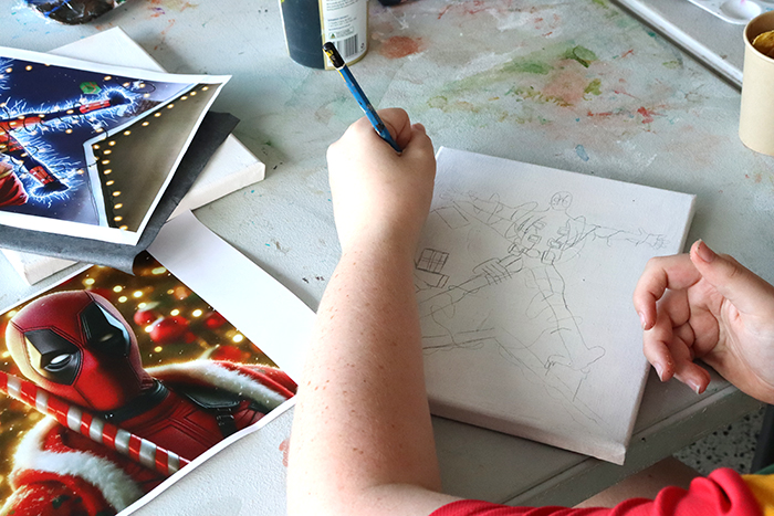 A photo of a kids hands drawing a picture of Spider Man 