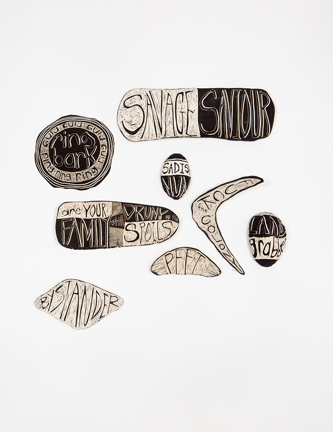 An installation of ceramic works in different shapes and sizes. They are black and white and have words on them