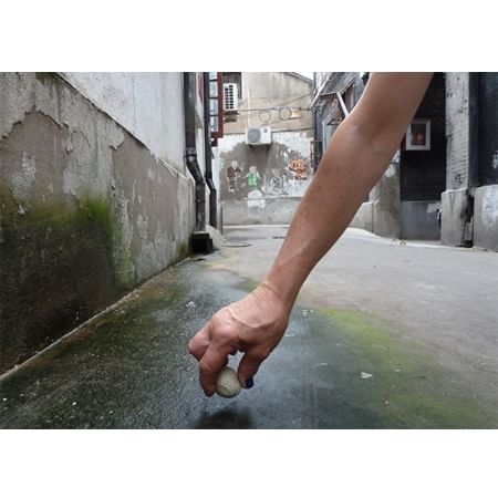 hand placing stone in ground in laneway