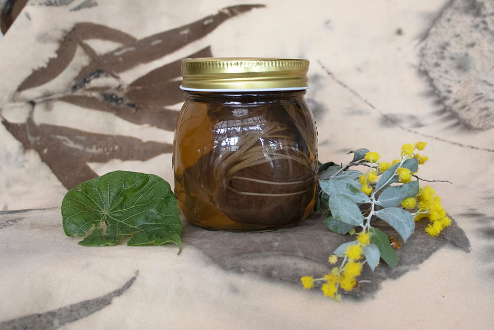 jar of natural dye with spray of wattle 