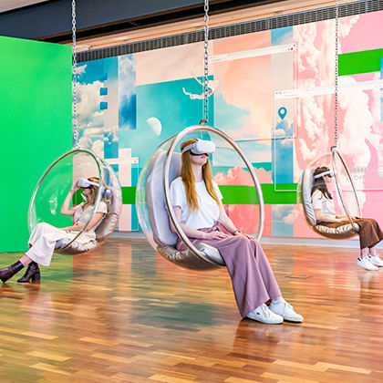 people in hang in circular chairs with virtual reality headsets on