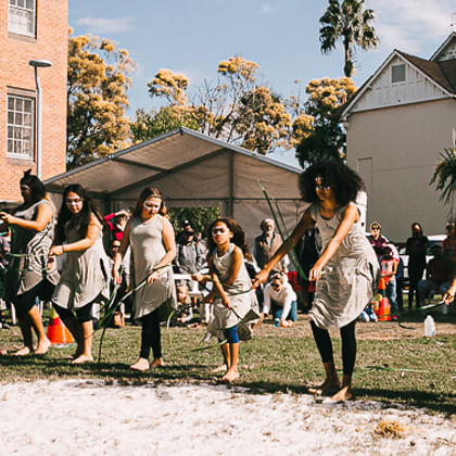 group of indigenous women and girls doing traditional dance with sticks