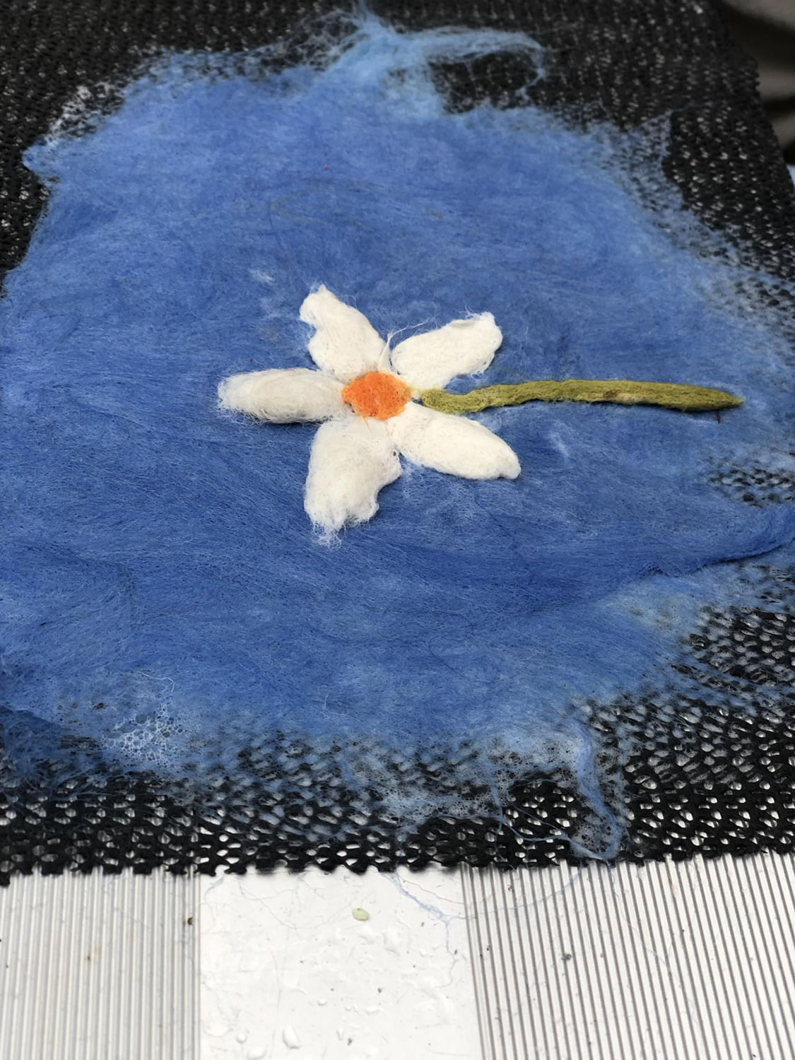 while flower on blue background created with wool fibre