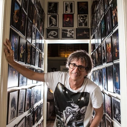 Tony Mott in narrow hallway with walls covered in his photographs 