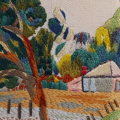 embroidery of landscape the a fence and shed with a tree in foreground and tree covered hill in background 