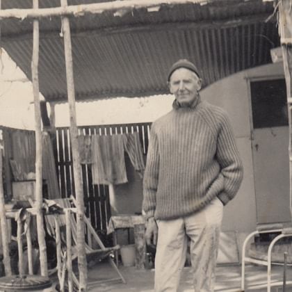 Artist Nutter Buzacott standing in front of old caravan