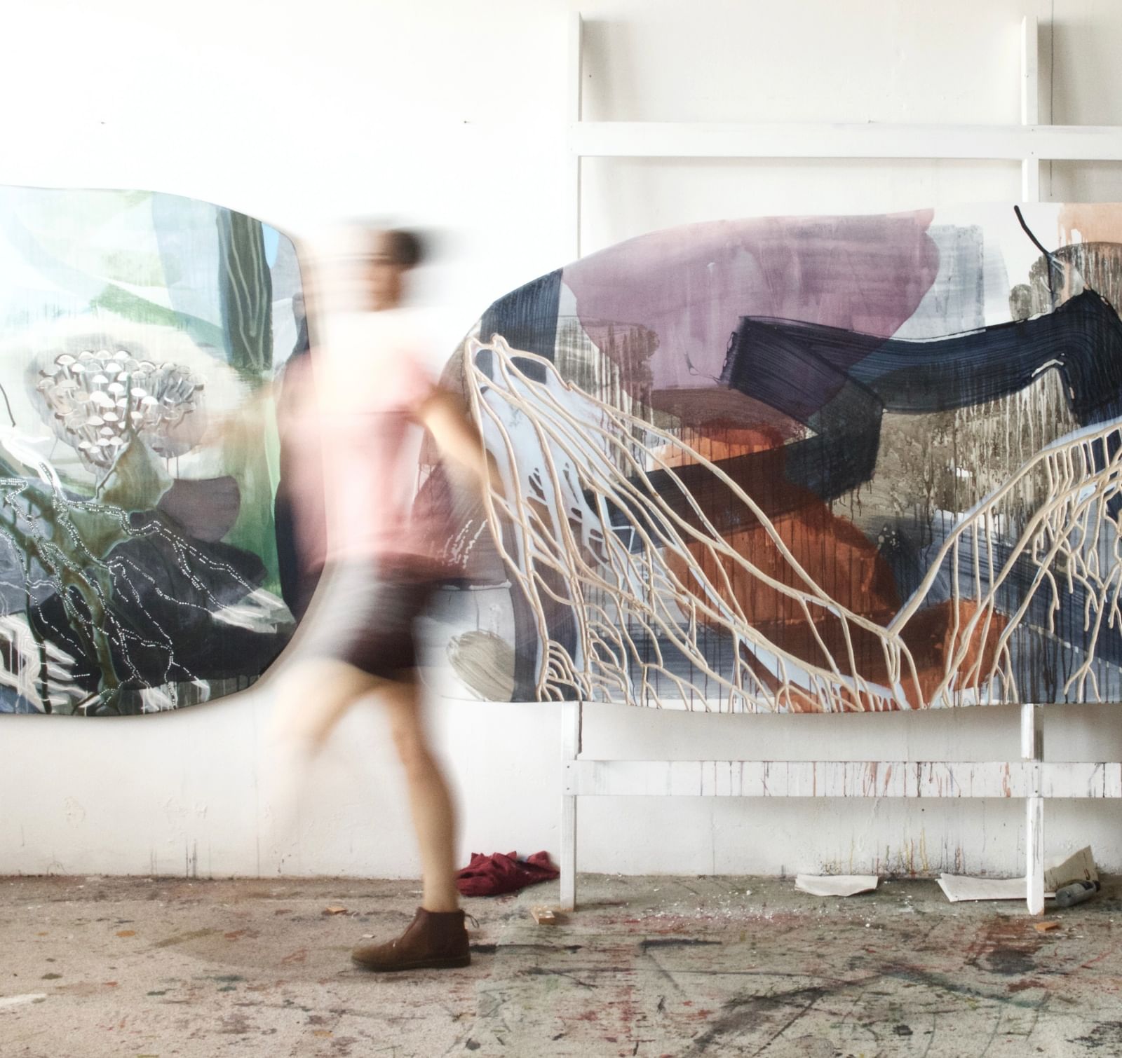blurred movement shot of Emma Walker in her studio with artworks behind her