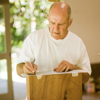Grant Vaughan drawing on paper on a large wooden block