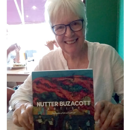 photo of Lee Dunn with the book she authored about artist Nutter Buzacott