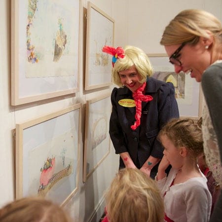 Peggy Popart with children and another woman looking at artwork