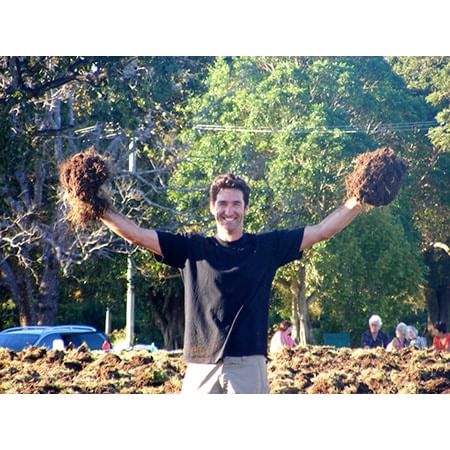 man holding clumps of soil and grass