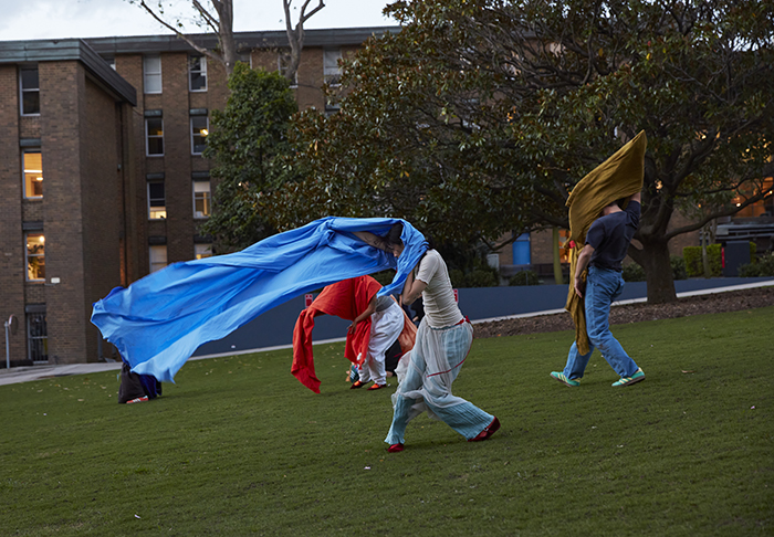 People in a park moving with large colourful fabric banners