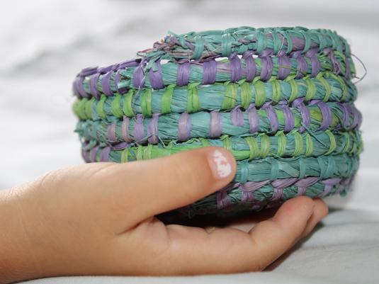 A child's hand holding a colourful woven basket