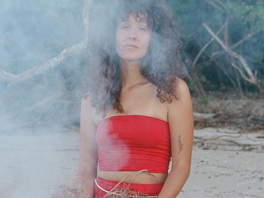 First nations musician, Nidala, pictured on the beach, wearing red