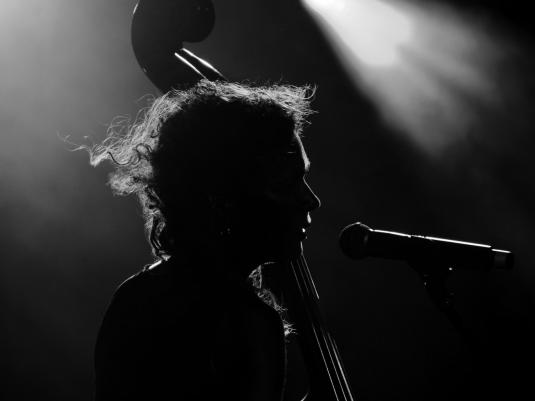 A black and white silouette of a woman playing double bass