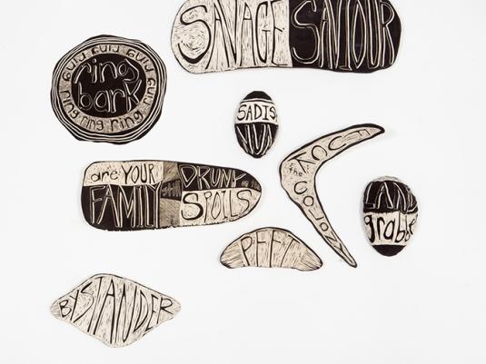 An installation of ceramic works in different shapes and sizes. They are black and white and have words on them