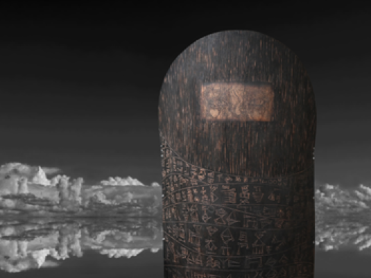 timber sculpture in foreground with a lake and reflected icey mountains in distant background.