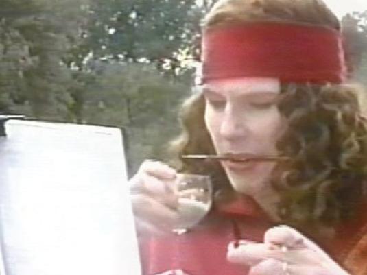 woman with paint brush between teeth looking at artwork on easel