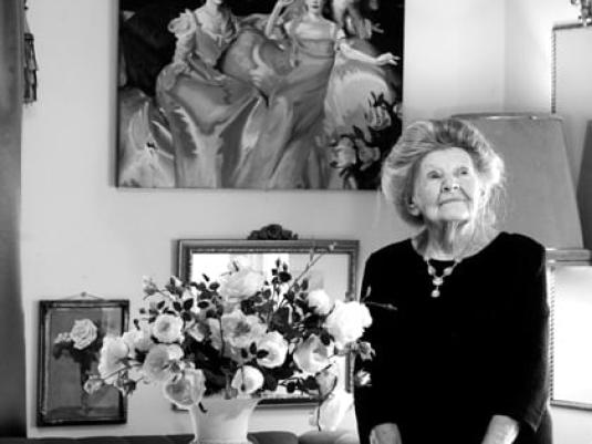 portrait of woman in her sitting room with a vase of flowers on table next to her