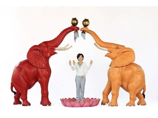 two elephants making arch with trunks with woman standing beneath it lotus flower