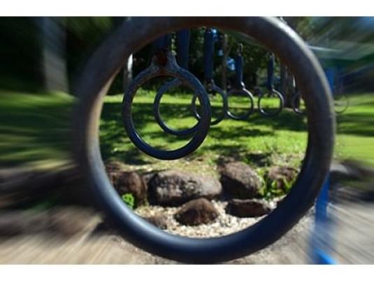 large circle in foreground with a row of hanging monkey bar rings going back into the distance int