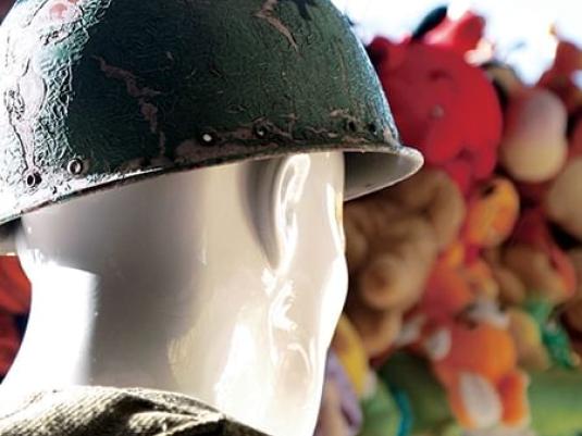 Headshot of statue with hard hat in foreground with stuffed toys in background