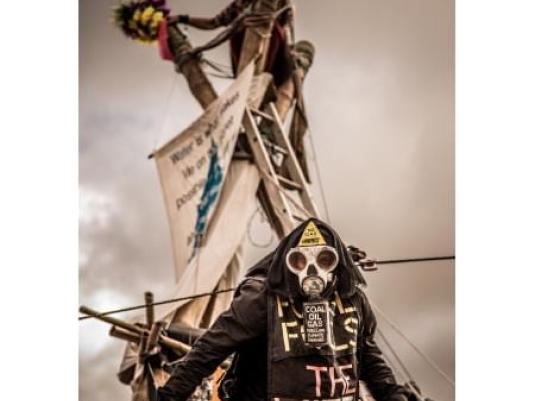 masked activist in front of protest tripod