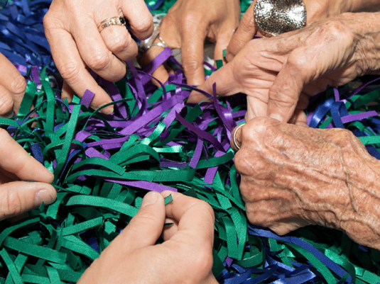 hands of multiple people in pile of strips of coloured material