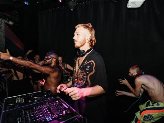 man at mixing desk with crowd behind him