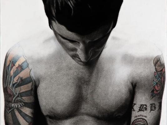 image of man looking downward with tattooed arms