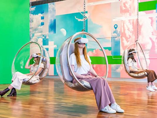 people in hang in circular chairs with virtual reality headsets on