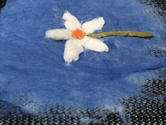 while flower on blue background created with wool fibre