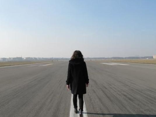 woman walking down the centreline of an airport runway