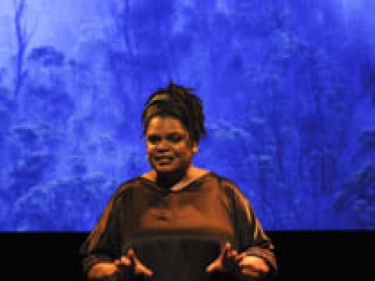 woman speaking in front of blue backdrop