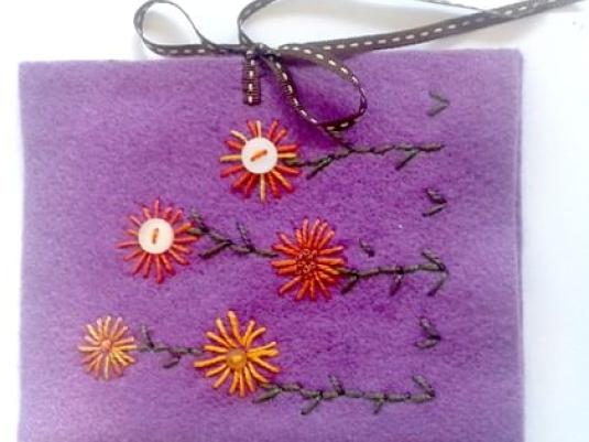 purple felt pouch embroidered with orange and gold flowers