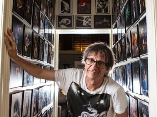 Tony Mott in narrow hallway with walls covered in his photographs