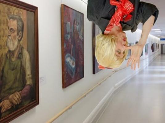 upside down Peggy Popart in corridor of artworks