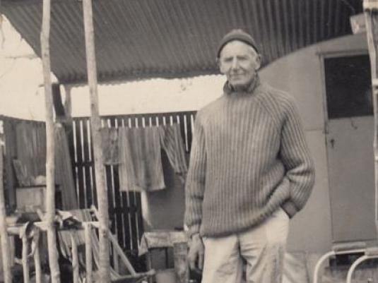 Artist Nutter Buzacott standing in front of old caravan