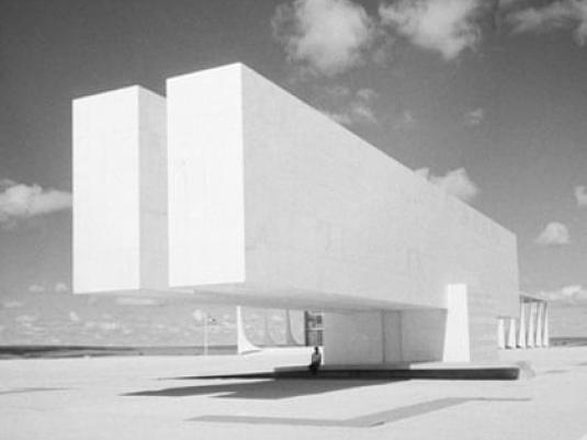 photograph of building that extends seemingly unsupported toward the viewer