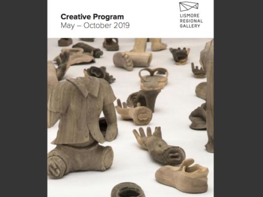 multiple wooden sculptures of of human body parts and clothing including hand, feet, shoes and a torso
