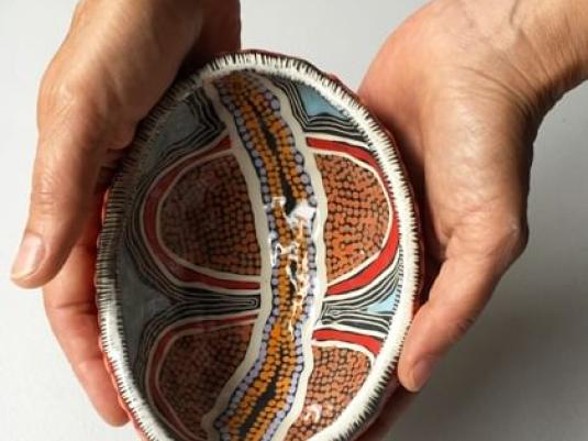person holding pot with Indigenous pattered glaze
