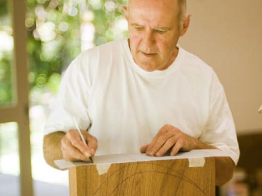 Grant Vaughan drawing on paper on a large wooden block