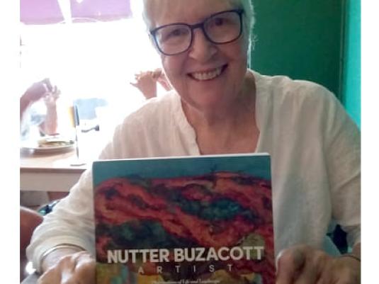 photo of Lee Dunn with the book she authored about artist Nutter Buzacott