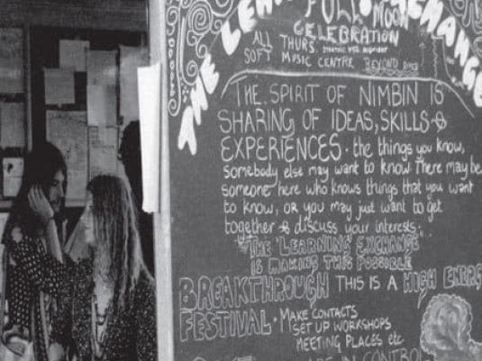 two people next to 'The Learning Exchange' blackboard at Aquarius Festival