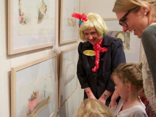 Peggy Popart with children and another woman looking at artwork